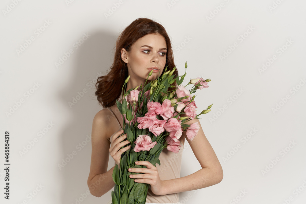 beautiful woman in dress posing flowers makeup light background