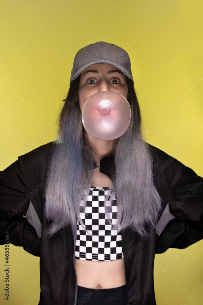  teenage girl wearing a cap making a bubble gum bubble
