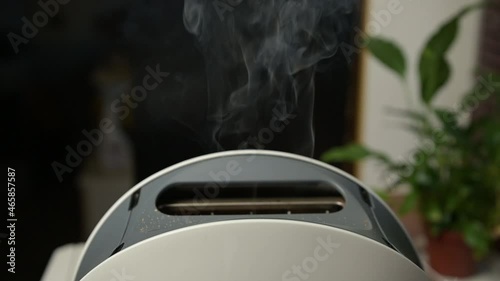 Burnt slices of bread fly out of the toaster slowly. Toaster smokes and fires burnt toast photo