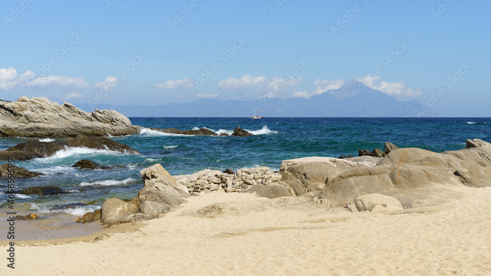 Sea shore sandy beach and waves. View to the rock and clouds. High quality photo