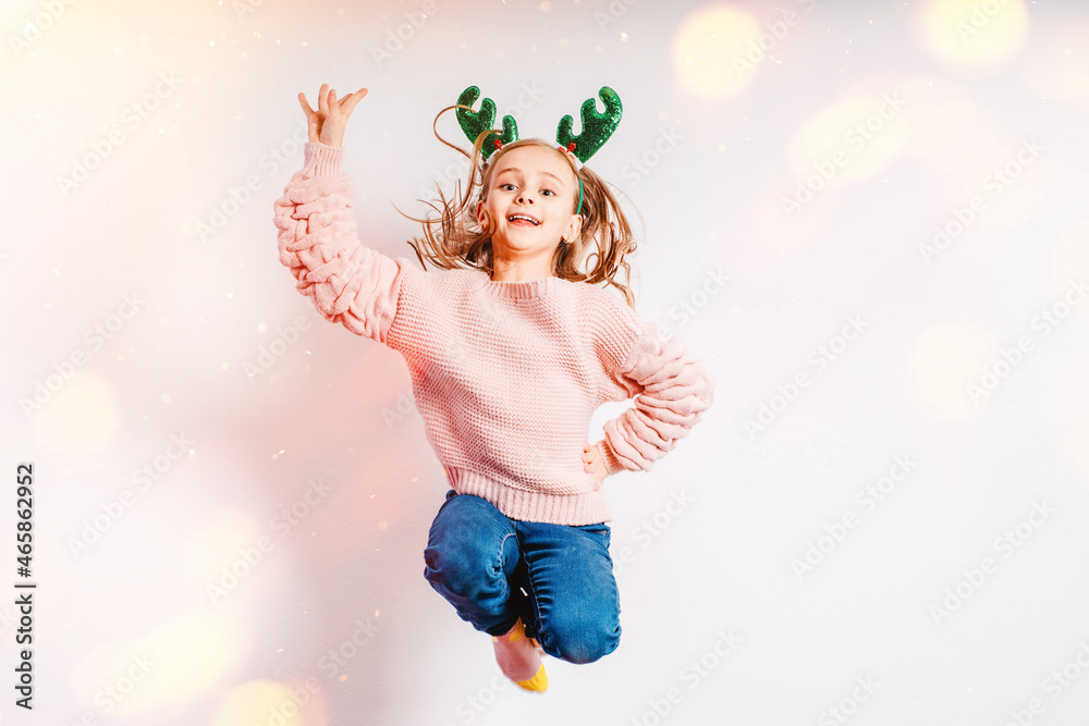 Cristmas concept. Little girl having fun wearing Christmas party glasses with reindeer antlers and red nose.Little girl in a Christmas mask on a light background, soft focus. Cristmas concept. Little girl having fun wearing Christmas party glasses with reindeer antlers and red nose.Little girl in a Christmas mask on a light background, soft focus.