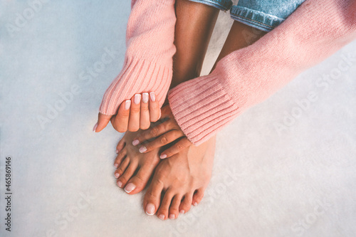 Stylish woman in pink sweater showing her beautiful nails with french manicure and pedicure. Nails after manicure and pedicure treatment. Copy space