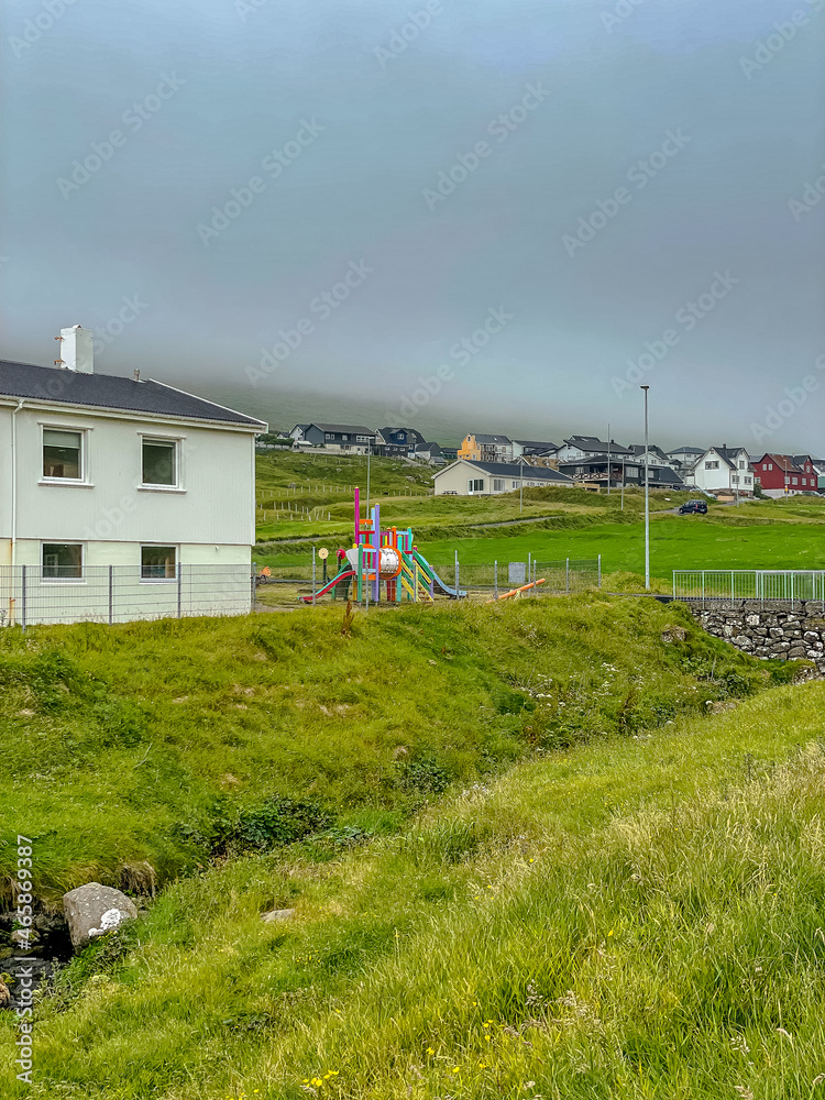 Fototapeta premium Beautiful aerial view of Faroe Islands Towns next to the ocean Canals, and boats and massive mountains.