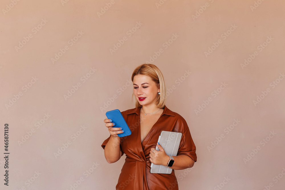 Young beautiful businesswoman in a brown dress talking on the phone with a laptop in her hands Young beautiful businesswoman in a brown dress talking on the phone with a laptop in her hands