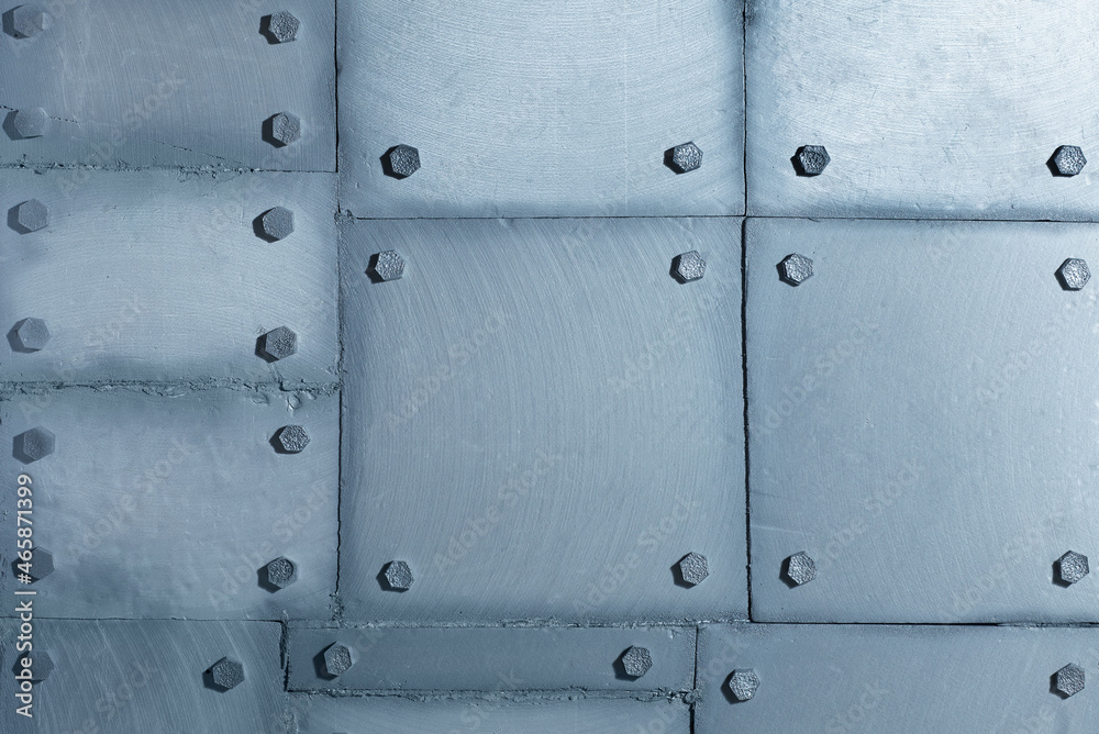 Background of silvery wall made of polyethylene foam sheets imitating metal with rivets.