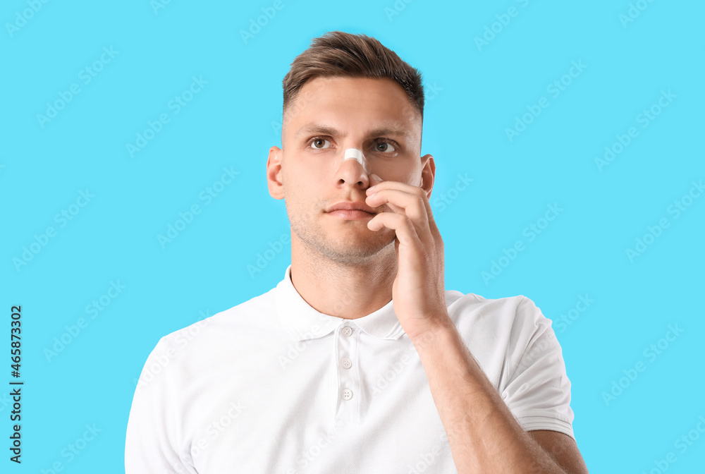 Man with medical patch on his nose against color background Man with medical patch on his nose against color background