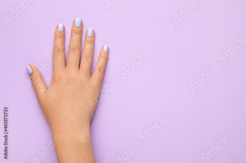 Female hand with beautiful manicure on purple background