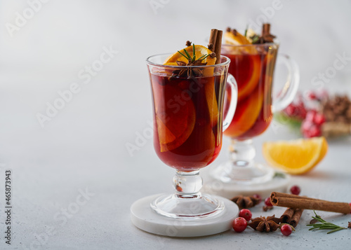 Hot seasonal alcohol beverage. Red mulled wine on white background. Gluhwein with cardamom, cinnamon stick, clove, orange slices, anise, fir needles, cranberries. Copy space, horizontal