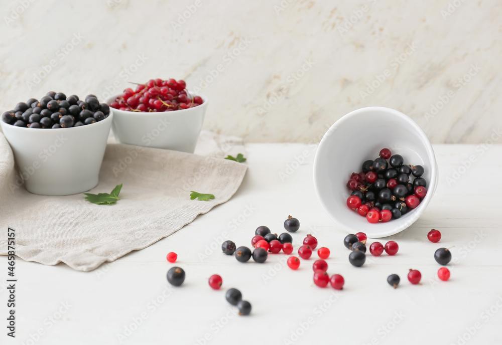 Bowl with tasty red and black currant on light background