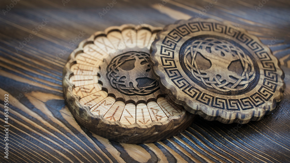 Blurred runes in a round wooden carved box on the table. Esoteric concept
