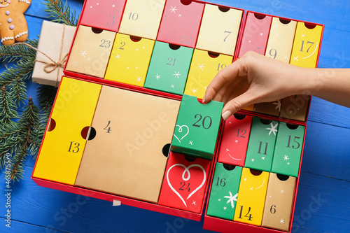 Woman with winter advent calendar on blue wooden background