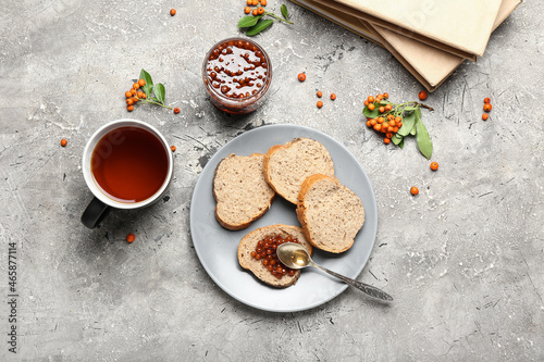 Plate with fresh bread, rowan berry jam and cup of tea on grunge background