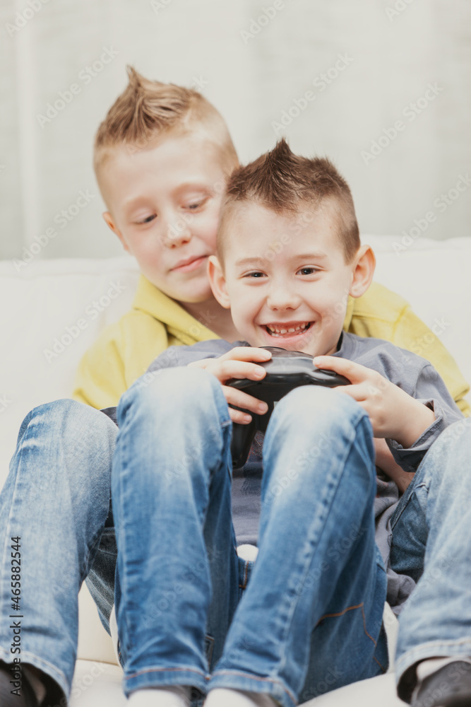 Two mischievous young boys playing video games together Two mischievous young boys playing video games together