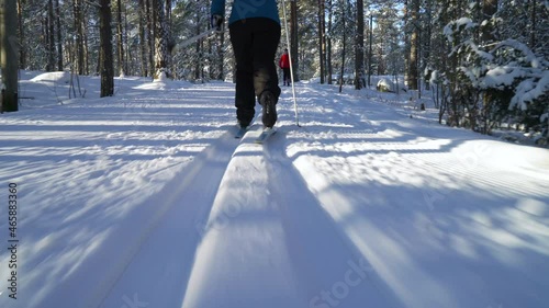 A woman going cross-country skiing in a frozen forest in Finland on a frosty sunny day. Steadicam Tracking Shot.