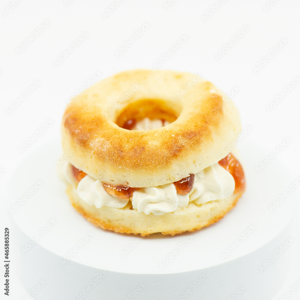 Closeup of a fresh baked scone with fresh cream and raspberry jam. Closeup of a fresh baked scone with fresh cream and raspberry jam.