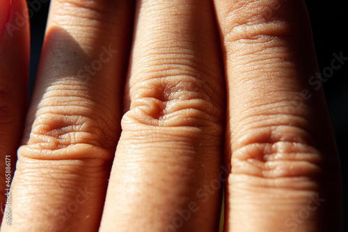 Black background, wrinkles on human fingers.