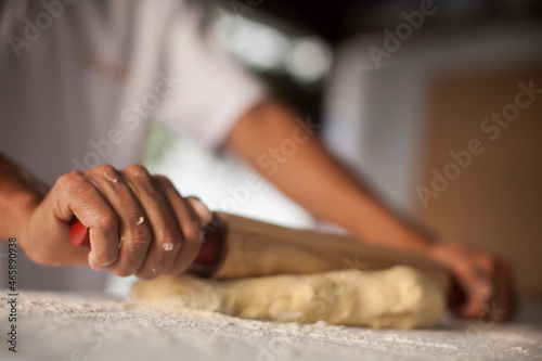 Human Hand using dough rolling pin to make pasta - making Raw and dry pasta on kitchen table - flower