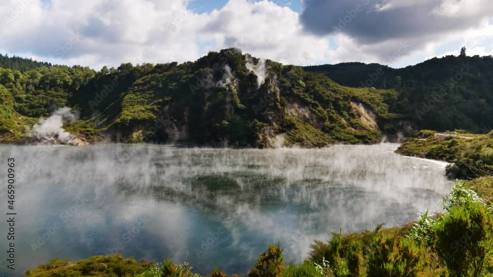 Tilt up shot of mysterious lake with hovering fog and smoke surrounded by volcanic mountain landscape in NZ. Tilt up shot of mysterious lake with hovering fog and smoke surrounded by volcanic mountain landscape in NZ.