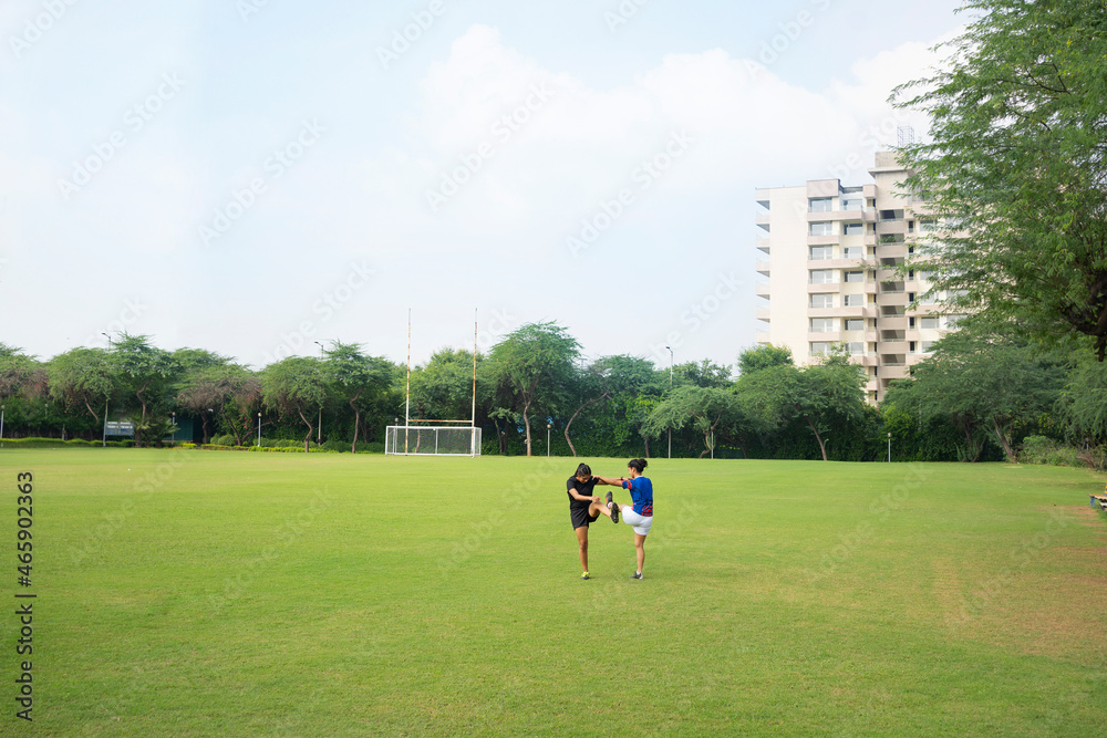 Two young athlete girls exercising together on the field Two young athlete girls exercising together on the field