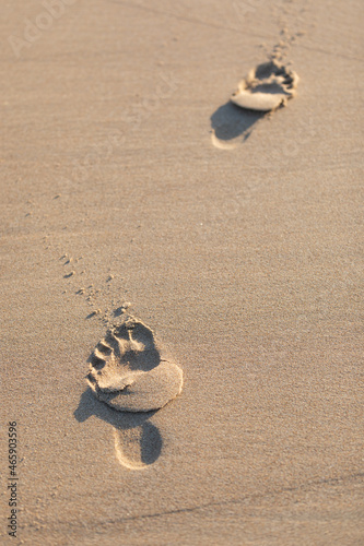 A person's footprints walking away from the camera, left in the sand on a beach