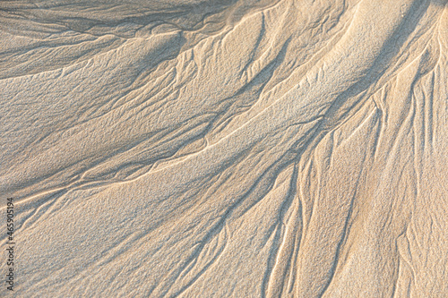 Patterns look like veins on the sand of a beach as left by the waves.