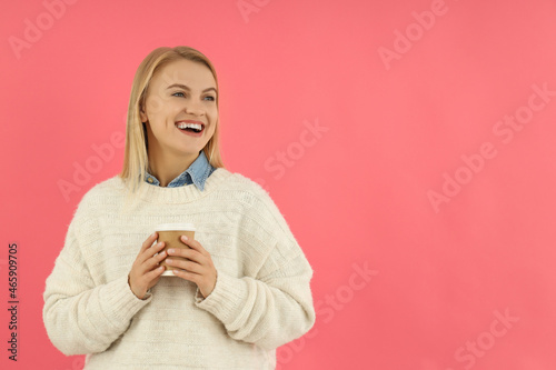 Attractive girl holds paper cup on pink background