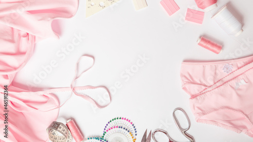 sewing business. Tailor's workplace with threads, scissors, template, spools, pink fabric. white background top view space for text in the frame. Tailoring concept