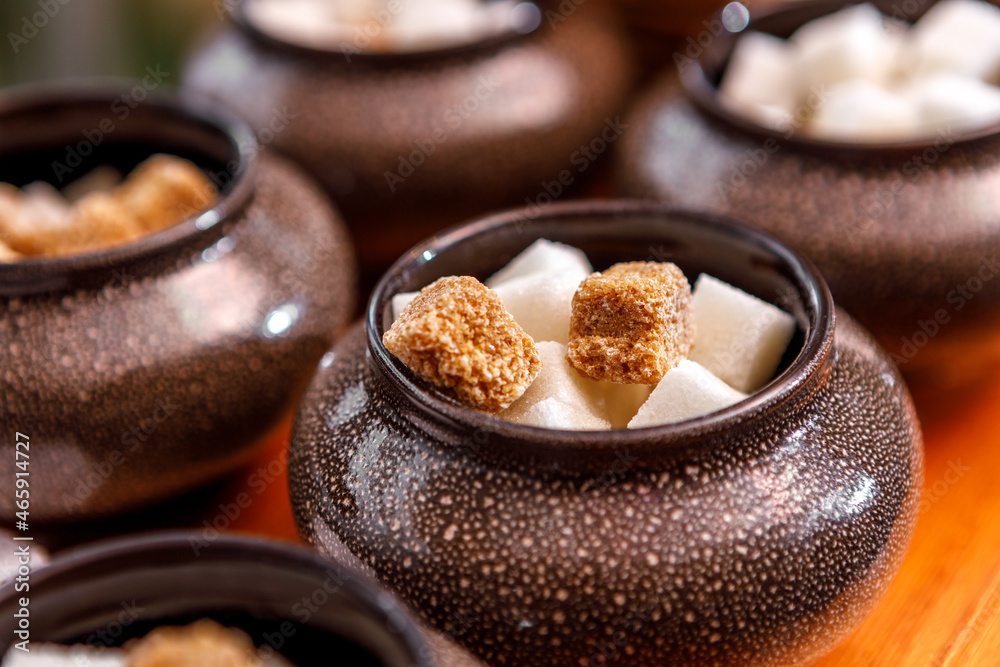 A sugar bowl with tongs filled with fruit sugar is on the table. A sugar bowl with tongs filled with fruit sugar is on the table.
