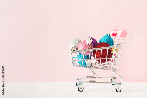 Shopping cart filled with colorful Christmas balls. Christmas and New Year holiday shopping concept