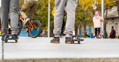 young boys ride on the sports field, on scooters and skates. street sports.