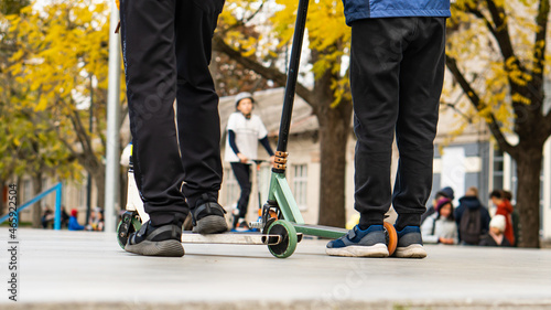 young boys ride on the sports field, on scooters and skates. street sports.