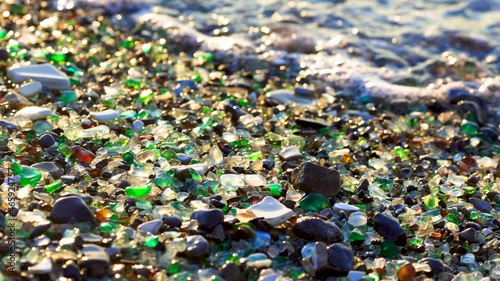 Glass Bay in Vladivostok. Close-up. Multicolored pieces of glass polished by the sea lie on the beach against the backdrop of sea waves. Glass beach.
