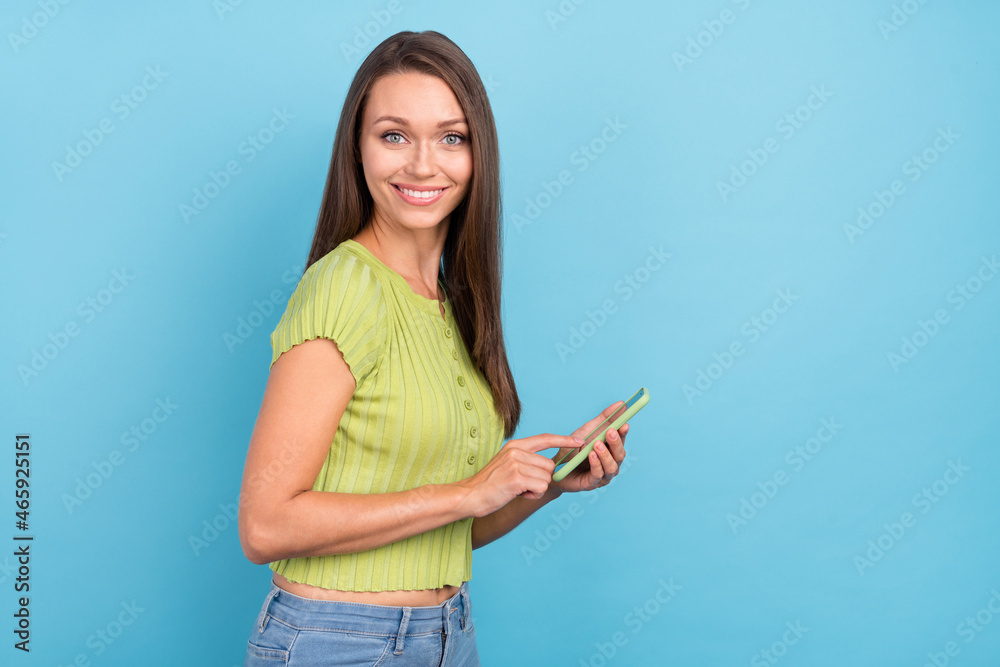 Photo of cheerful happy positive young woman hold phone post comment like blog isolated on blue color background Photo of cheerful happy positive young woman hold phone post comment like blog isolated on blue color background