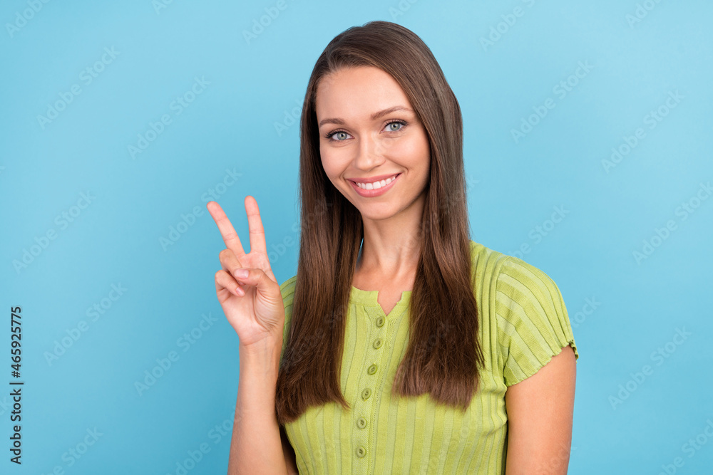 Photo of cheerful positive young woman make finger v-sign cool mood isolated on pastel blue color background Photo of cheerful positive young woman make finger v-sign cool mood isolated on pastel blue color background