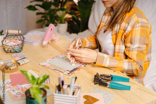 Cropped shot of women making homemade scrapbooking album from paper. DIY, hobby concept, gift idea, decor with handcraft attributes, home production, the process of creation, creativity.