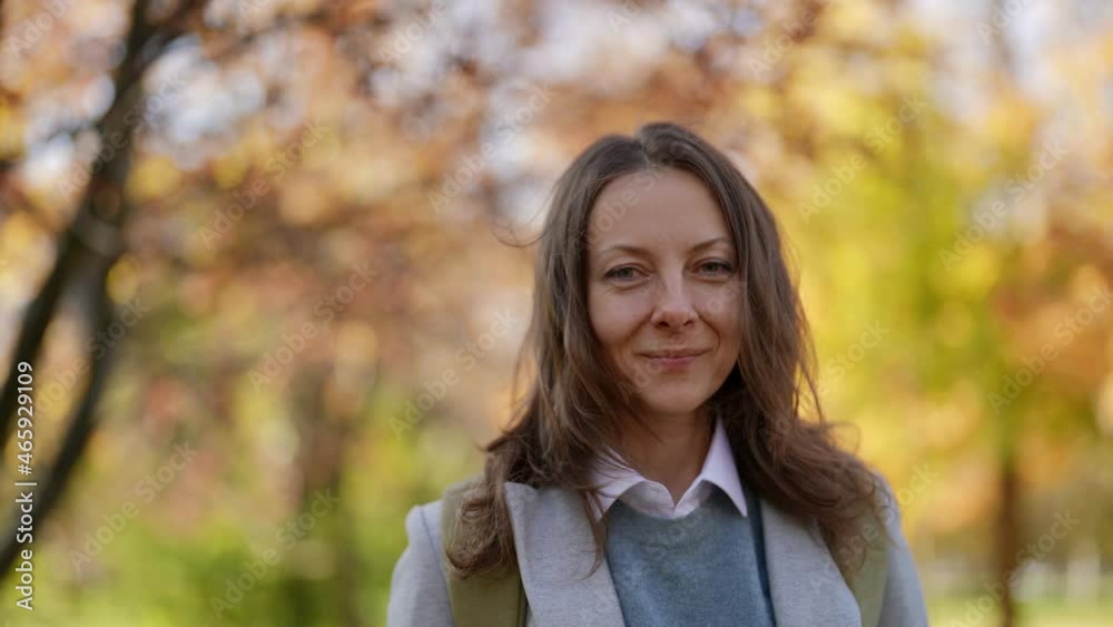 Portrait of an adult female model looking into the camera smiling in autumn in the city park Portrait of an adult female model looking into the camera smiling in autumn in the city park
