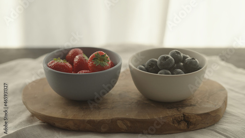 fresh blueberries and strawberries in ceramic bowls with natural light