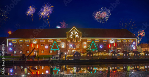 New Year celebrations on New Years Eve with fireworks. View of the harbor with the famous Christmas market on two floors in the historic warehouse on the port of Toenning, Schleswig-Holstein, Germany. photo