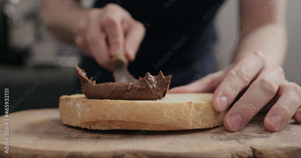 man spreading chocolate hazelnut spread on bread slice on wood board man spreading chocolate hazelnut spread on bread slice on wood board