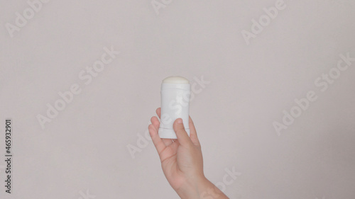 woman holding a white stick deodorant with her hand.