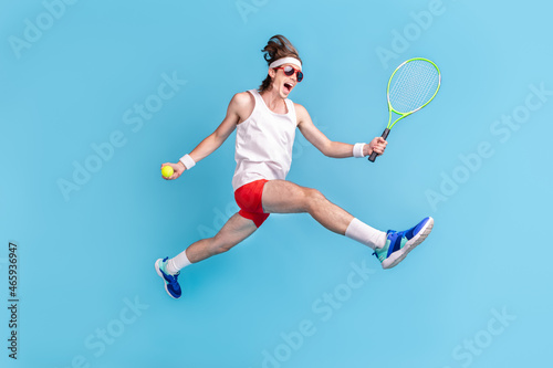 Full length body size photo man jumping up playing tennis on court isolated pastel blue color background © deagreez