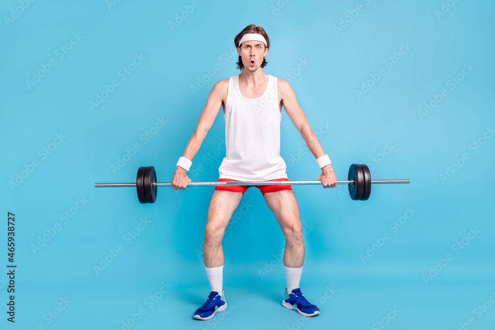 Full length body size photo man keeping barbell wearing sportswear isolated pastel blue color background Full length body size photo man keeping barbell wearing sportswear isolated pastel blue color background