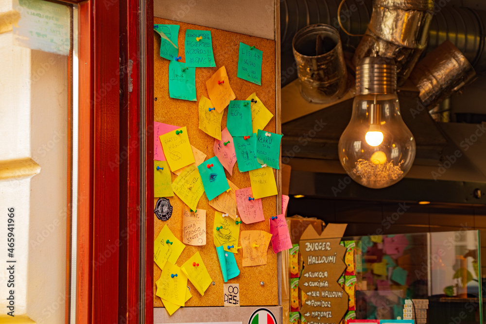 kolorowe notatki z przypomnieniami i notatkami przy wejściu do zabytkowej kawiarni młodzieżowej w Europie ogromne ciepłe lampy metalowa folia i rury w stylu grunge loft - obrazy, fototapety, plakaty 