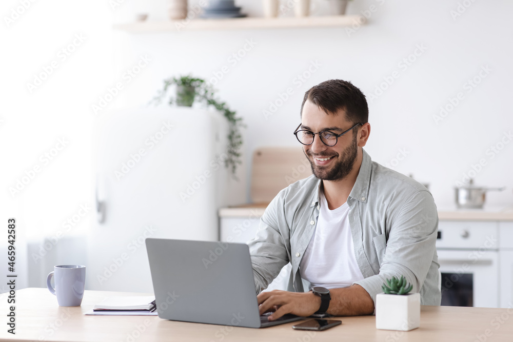 Happy handsome mature european male teacher or businessman with beard in glasses working at laptop Happy handsome mature european male teacher or businessman with beard in glasses working at laptop