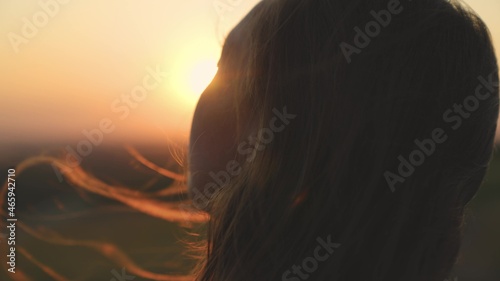 young girl looks at sunset and prays, religious person, her hair is flying in wind in glare of the sun, to believe in goodness, a woman's dream of love, to think and ask for forgiveness from heaven © Валерий Зотьев