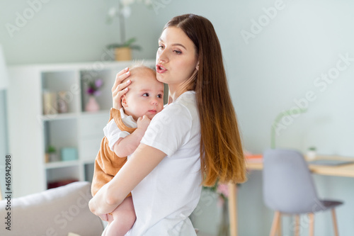 Photo of charming shiny lady wear white t-shirt smiling holding arms hands baby singing song inside indoors house room