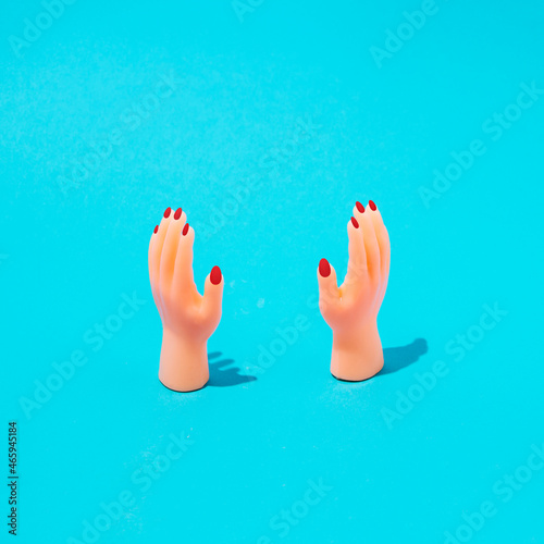 Female hands with red nails on a sky blue background. Minimal beauty concept.