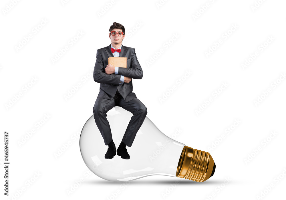 A young businessman sits on a light bulb