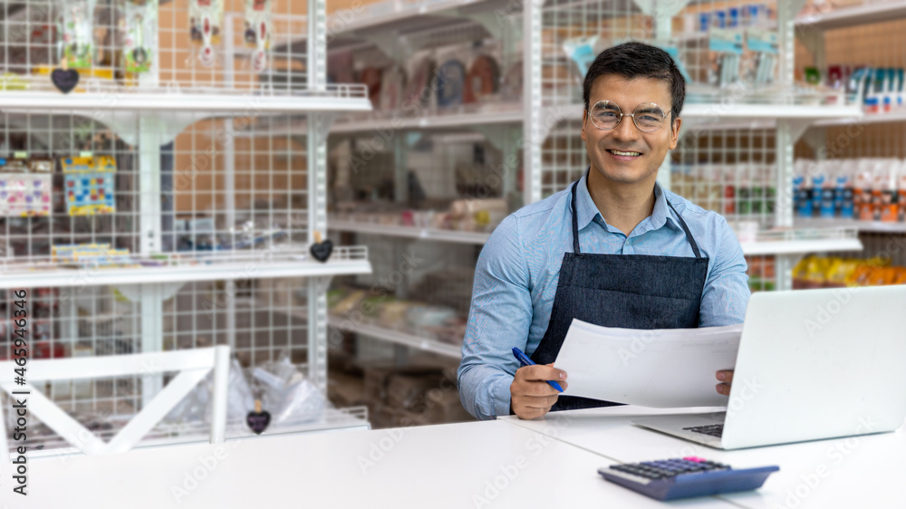 Young male owner uses computer and software to check stocks and goods in his startup bakery or café shop. Smart male shop owner uses technology to improve his online business and increase his sales