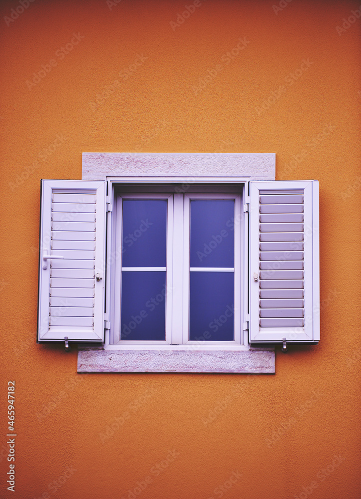 white window with shutters on a yellow house